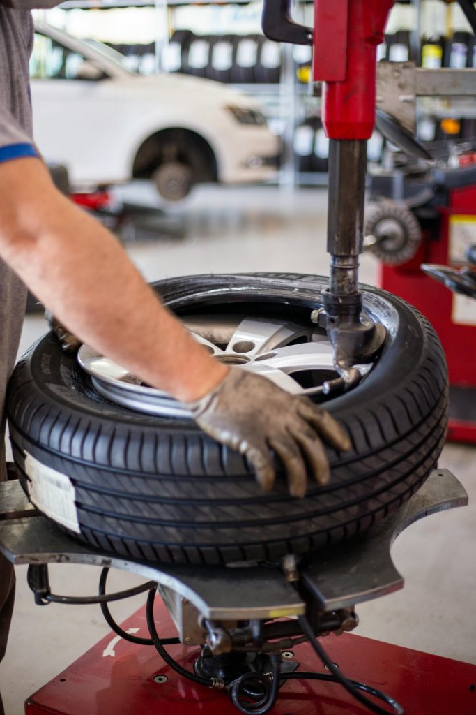 Close-up of an auto mechanic changing a tire with precision equipment in a professional workshop.