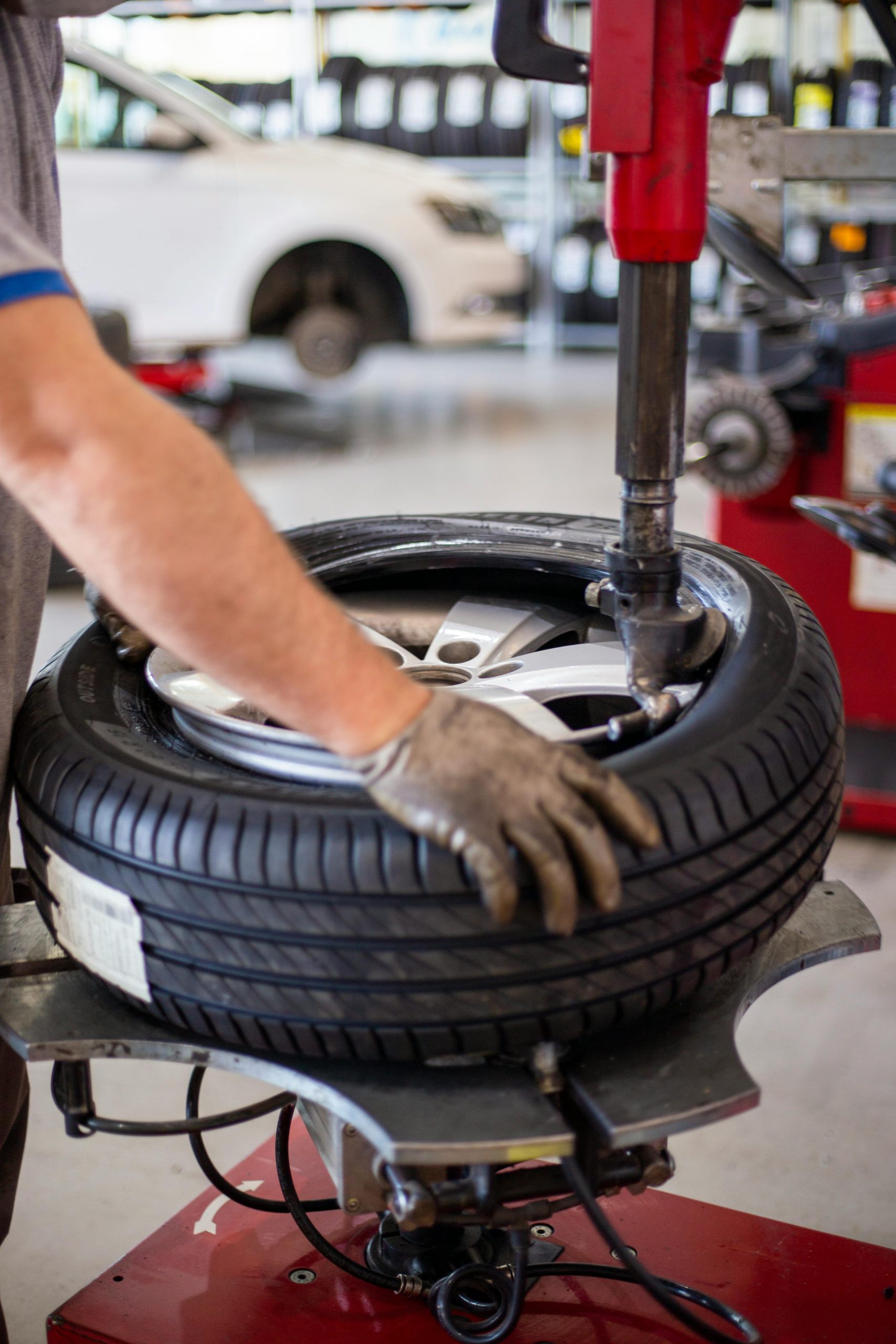 Close-up of an auto mechanic changing a tire with precision equipment in a professional workshop.